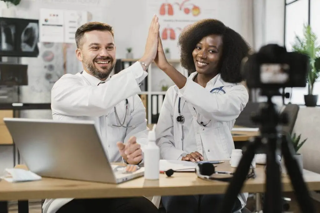 Social Media Marketing: A Path to Business Success Social Media Marketing Diverse doctors giving high five during vlog recording